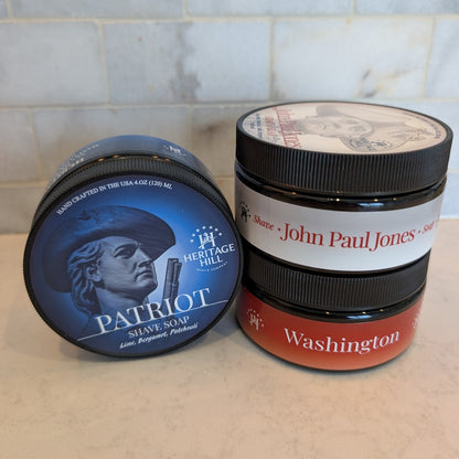 Three cylindrical containers labeled 'Patriot', 'John Paul Jones', and 'Washington' on a tiled bathroom counter.