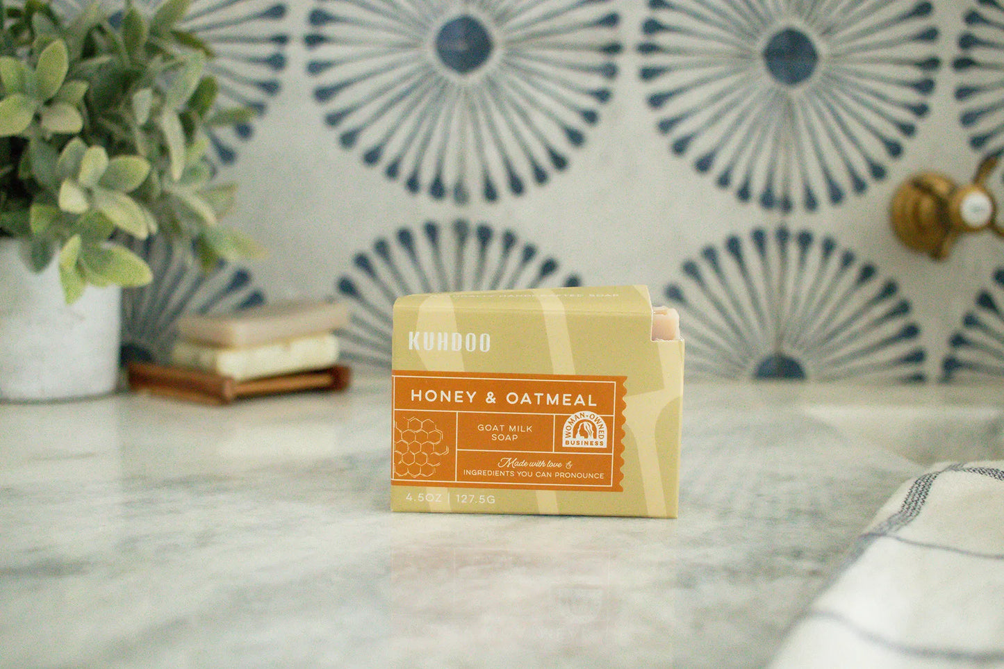 Bar of soap with a label on a marble surface, decorative tiles in the background