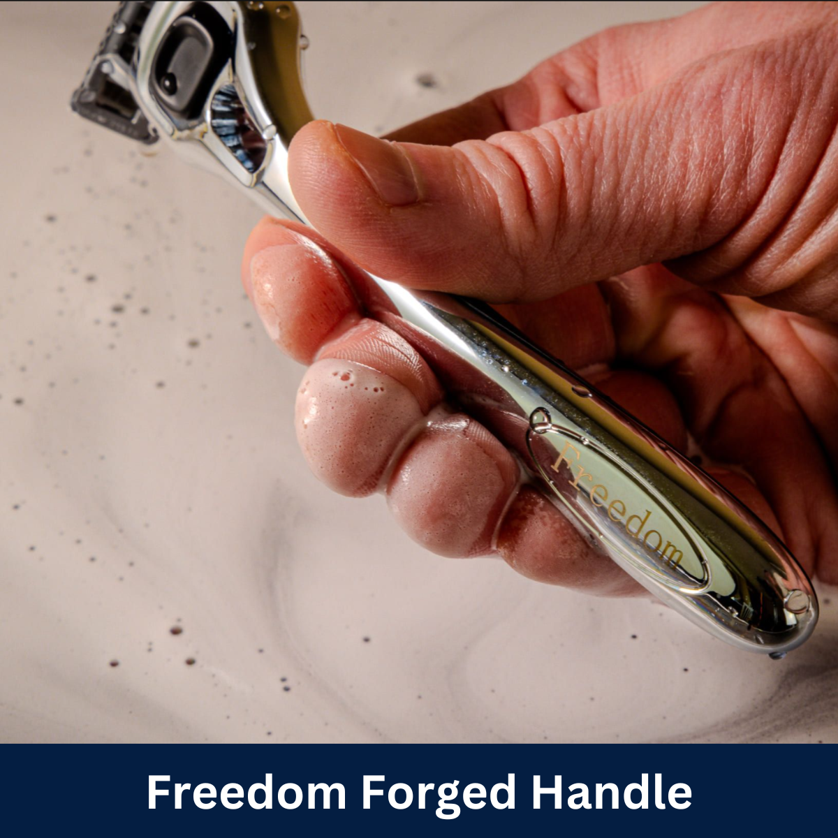 Polished silver alloy shaving razor handle with Freedom logo and soapy water in background