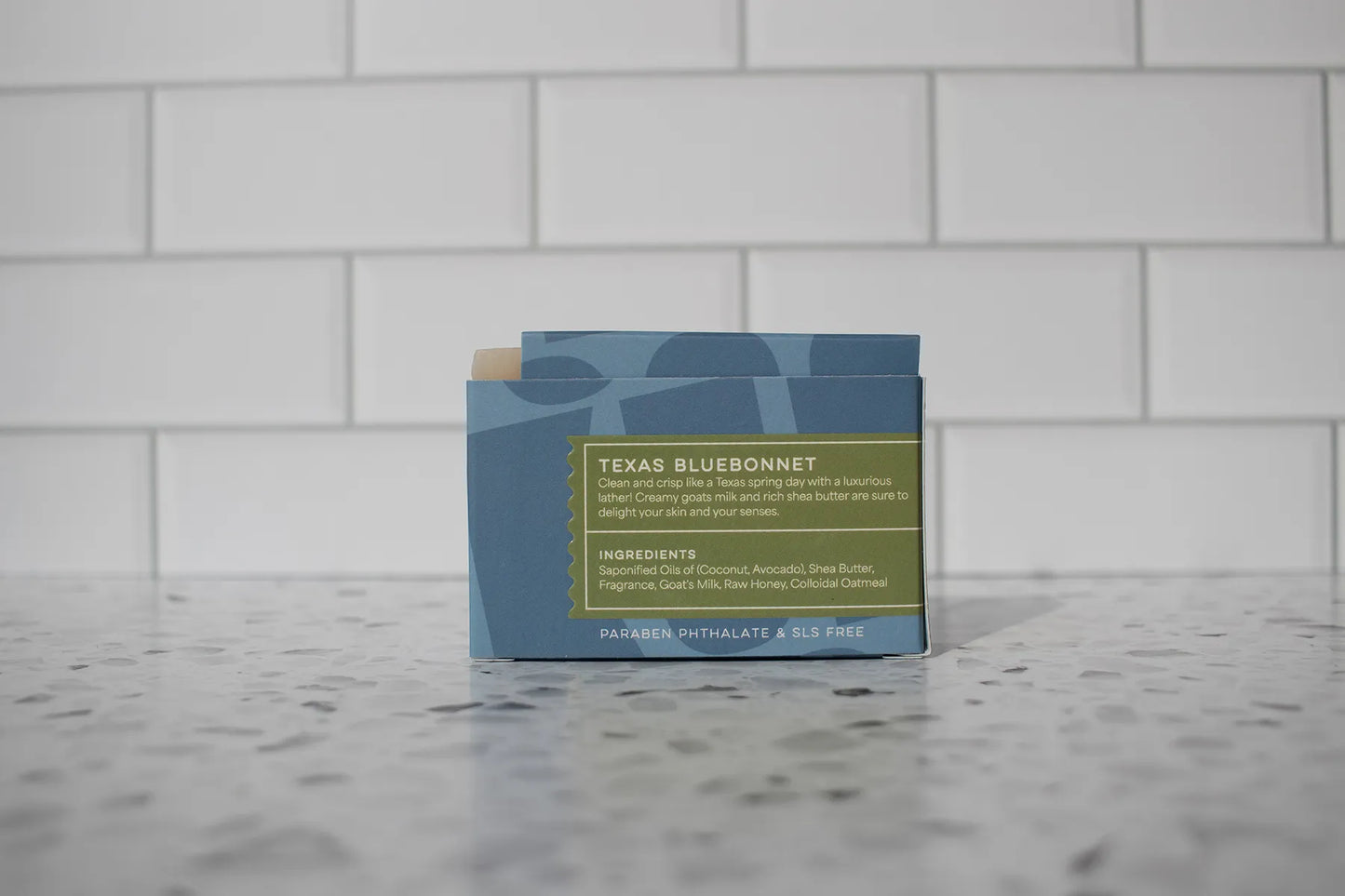 Bar of soap with a label on a marble surface against a tiled wall background